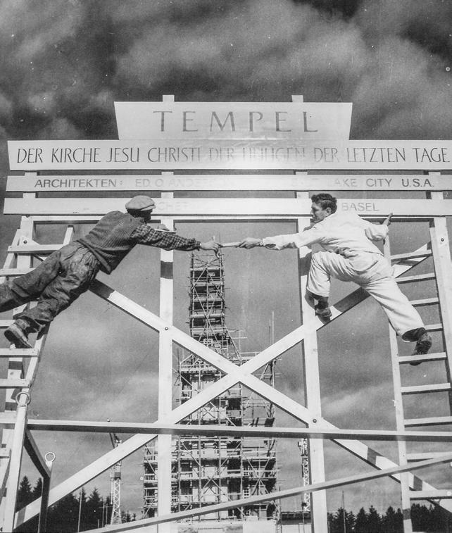 작업자들이스위스베른성전건축부지에서표지판을세우고있다.